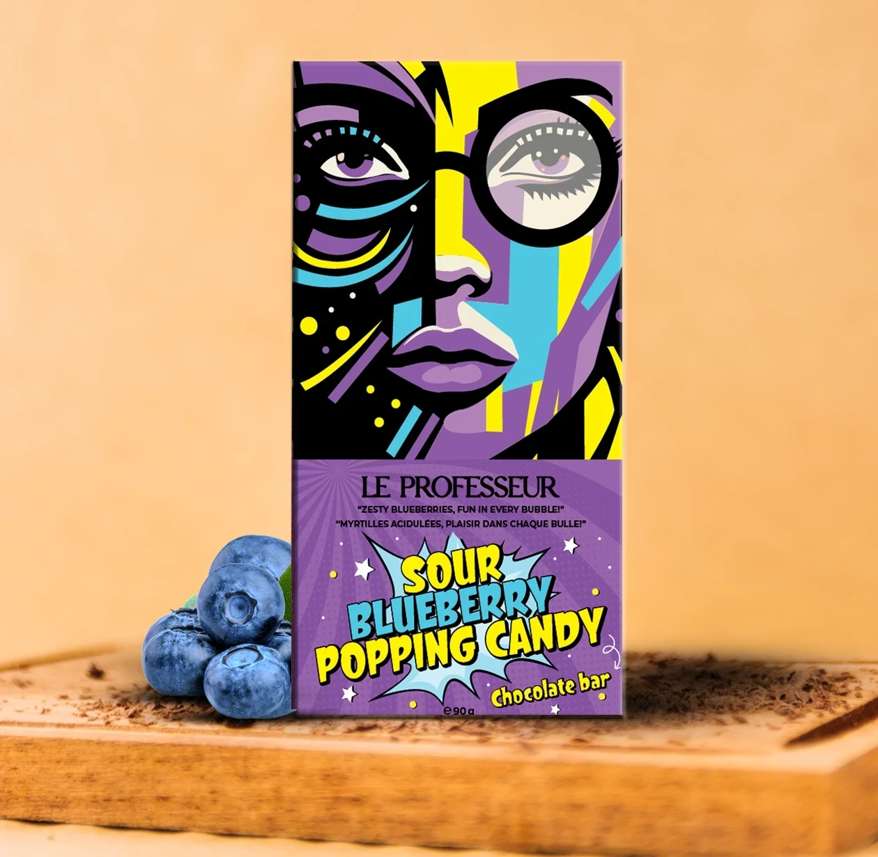 Le Professeur Sour Blueberry Popping Candy chocolate bar with vibrant pop-art packaging and fresh blueberries.